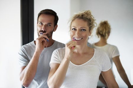 Couple brushing teeth after periodontal treatment and trying to keep their mouth healthy. 